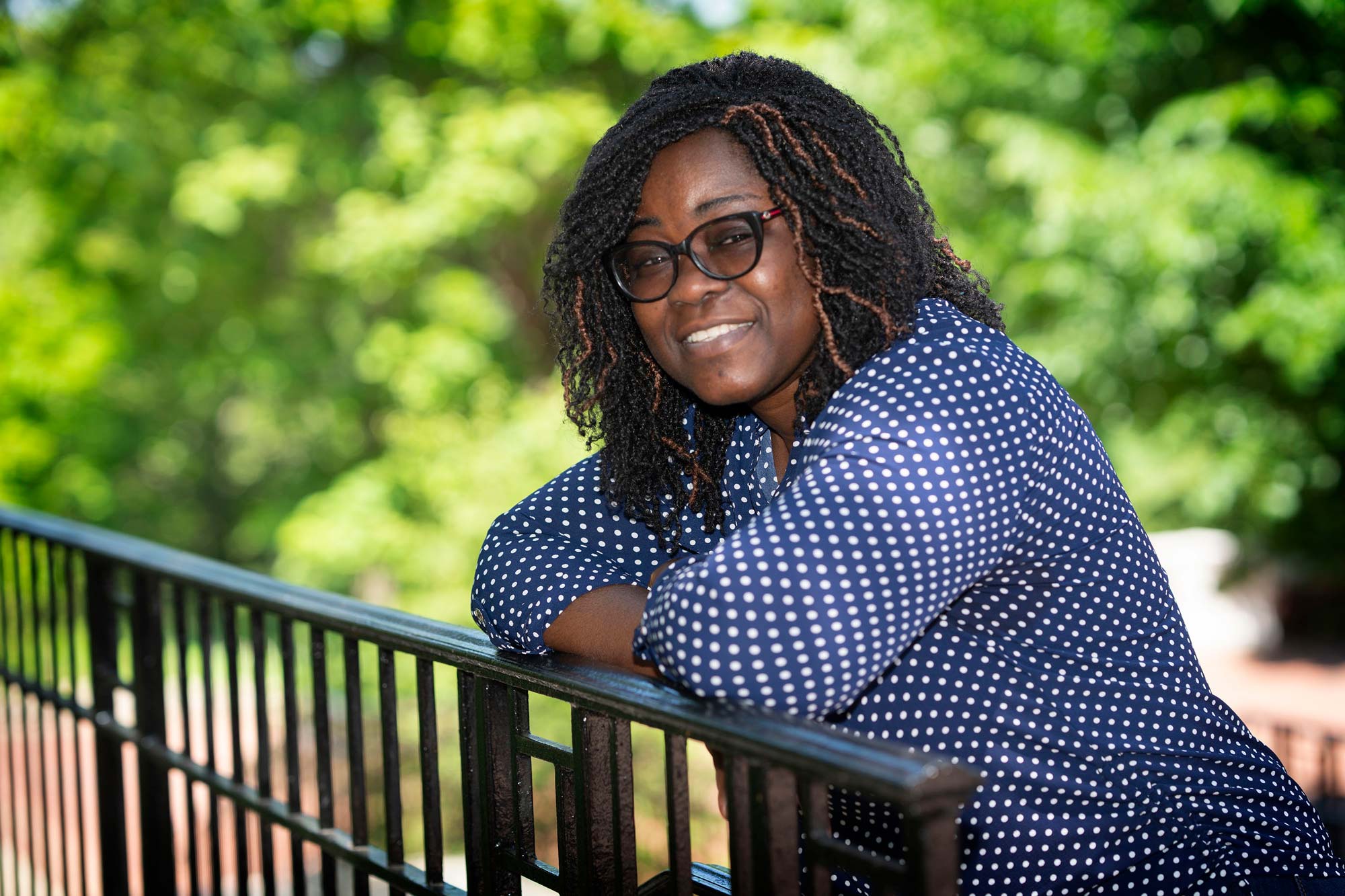 Nana Boateng leans on a railing in a blue and white shirt. 
