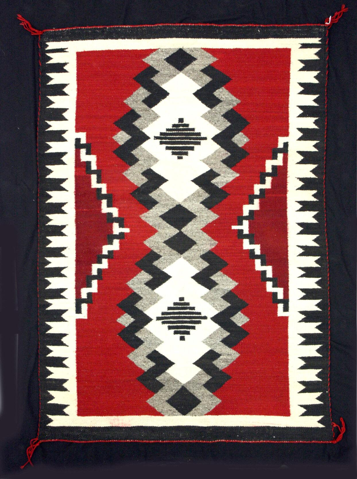 A rug with varied patterns in red, black, and white