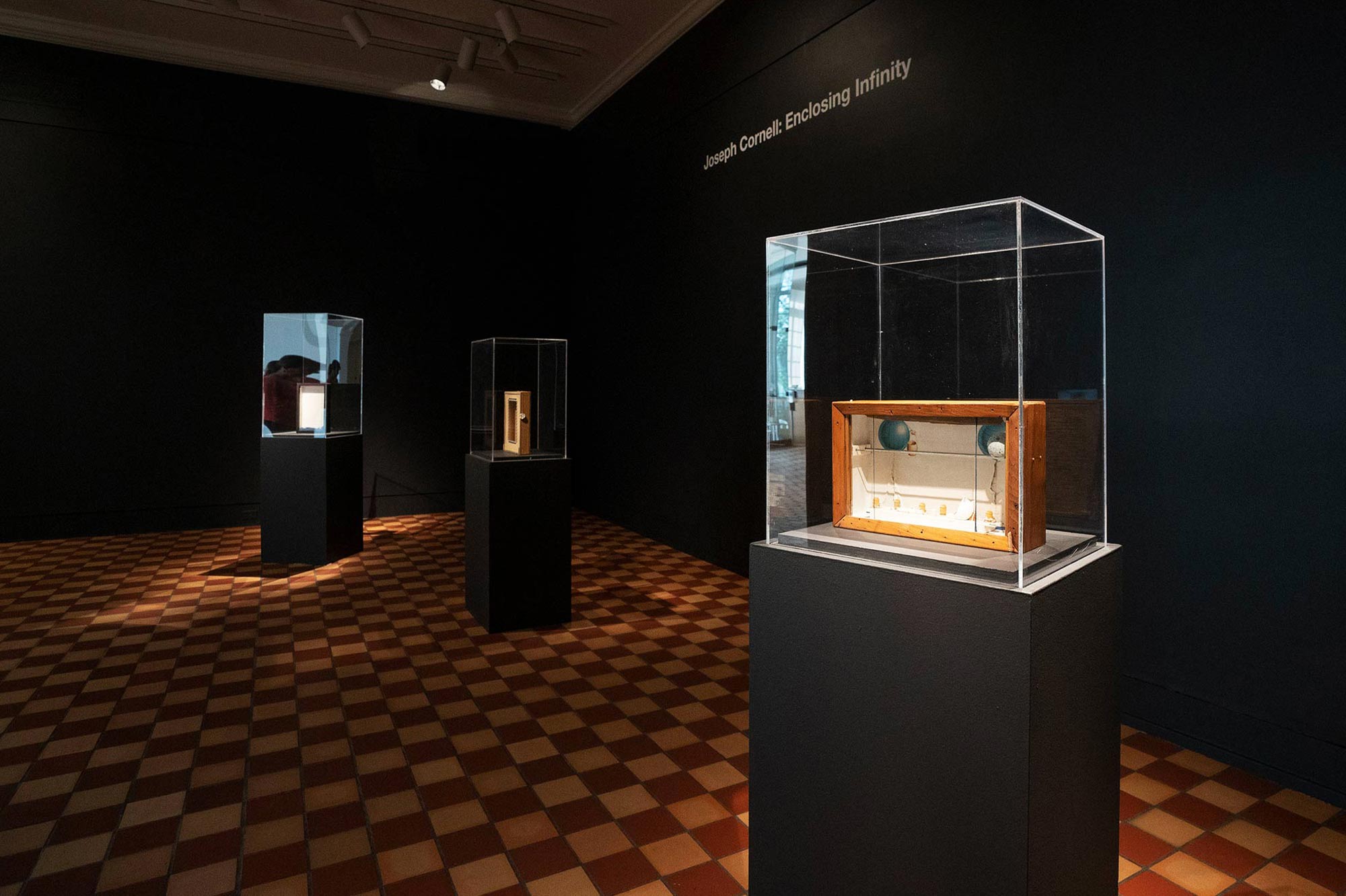 An artwork sits in a glass case at the Fralin, with other artworks in the background. 