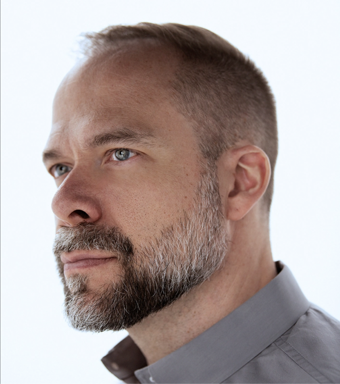 A man stands staring off to the left of the screen.