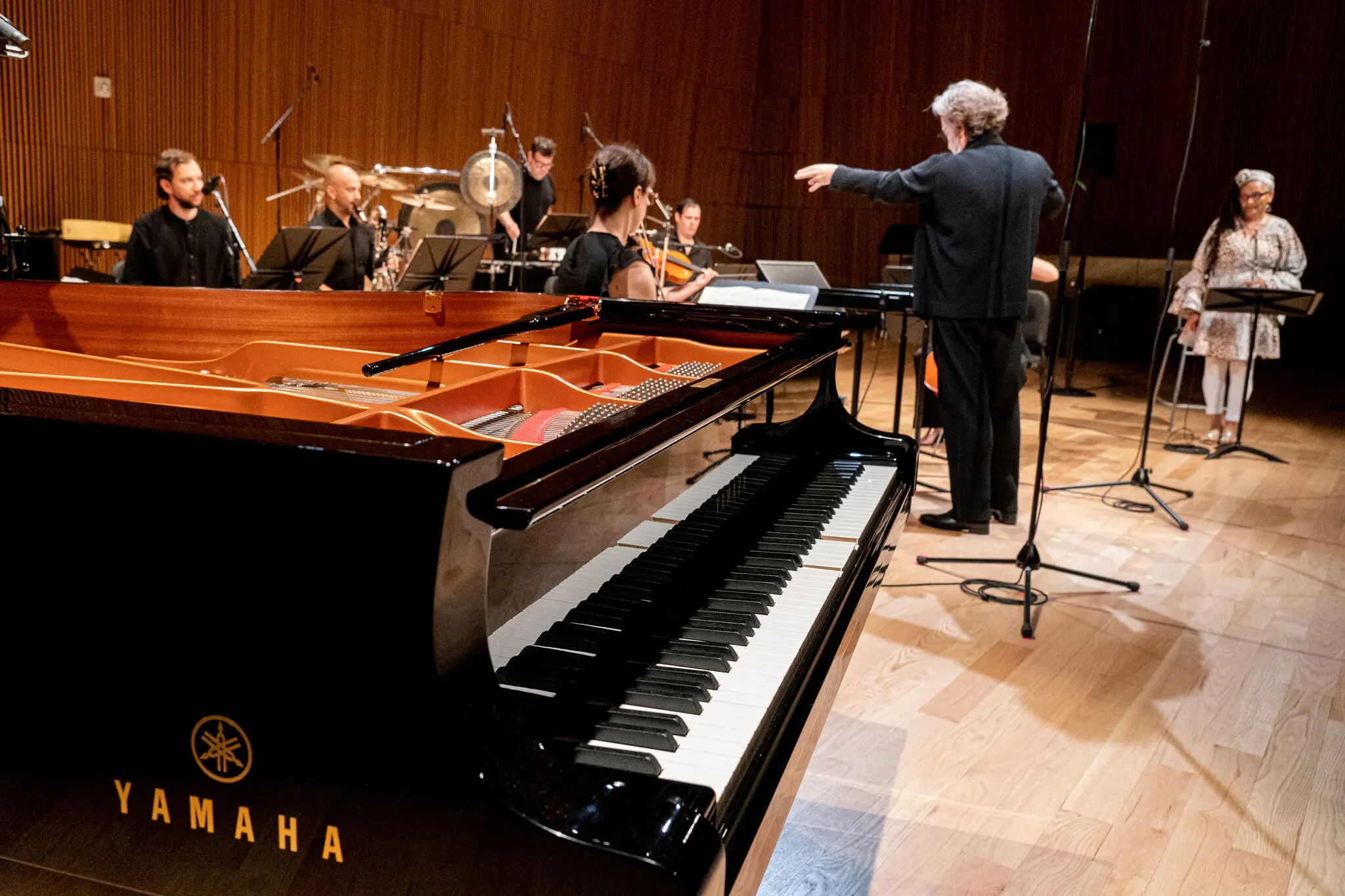 It plays itself: Brad Lubman conducts the Ensemble Signal on Friday, with Nicole Mitchell, right. In the foreground is the Disklavier piano, controlled by Voyager software, which was running on a nearby computer.Credit...Stephanie Berger