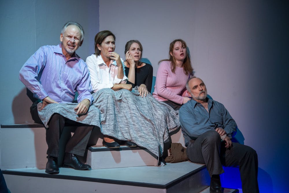 An image of five people sitting on stage