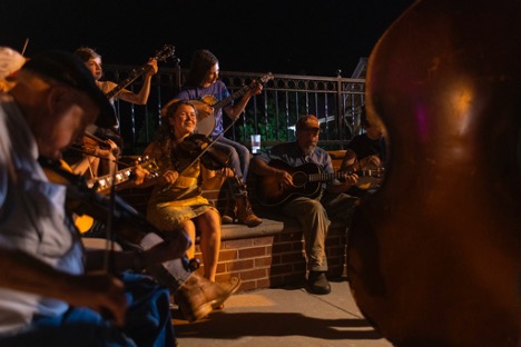 Mac Traynham, right, jams with children on the sidewalk outside the Floyd Country Store on 5/20/22. Pat Jarrett/Virginia Humanities
