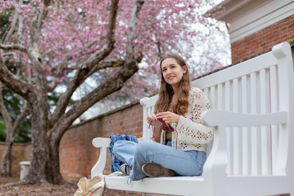 an image of a girl doing yarn work on a bench