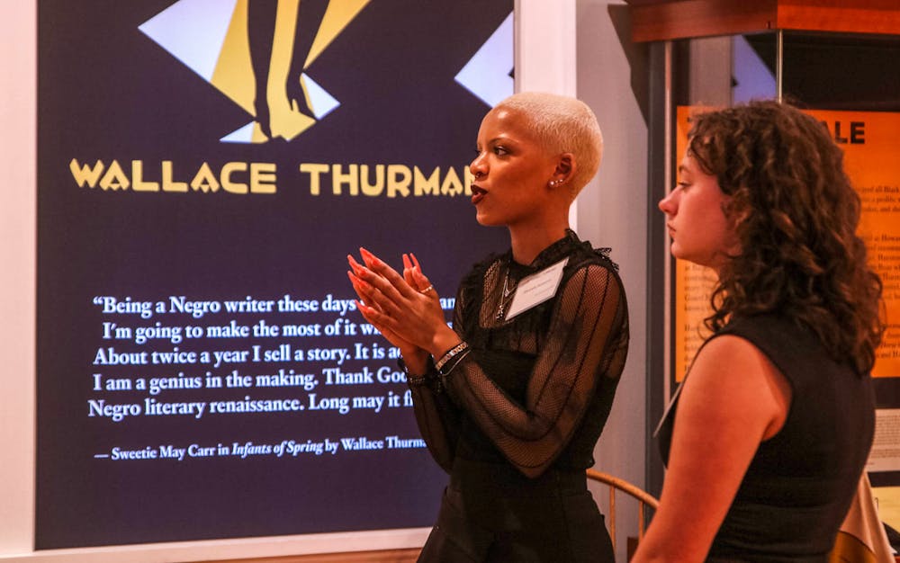 Two people in profile view stand before a banner that reads "Wallace Thurman" with a quote from the writer. 