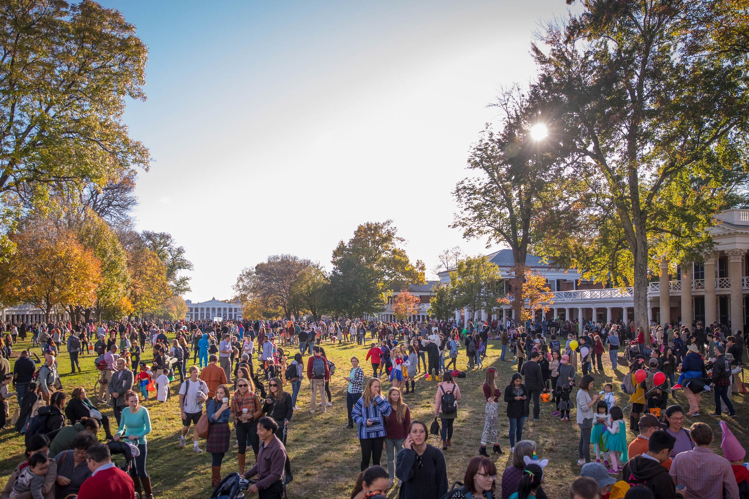 Crowds of students, families, and children gather in the middle of the lawn on a late afternoon for Trick-or-Treating on the Lawn.