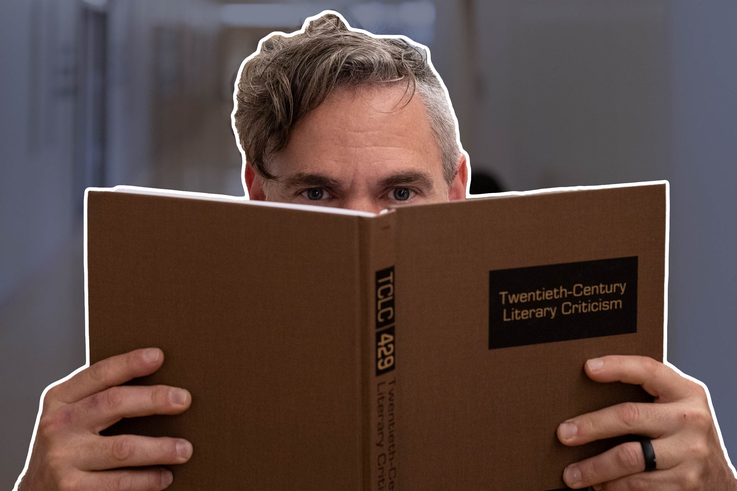 Professor Stanley Stepanic peers over a book whose cover reads, "Twentieth Century Literary Criticism."