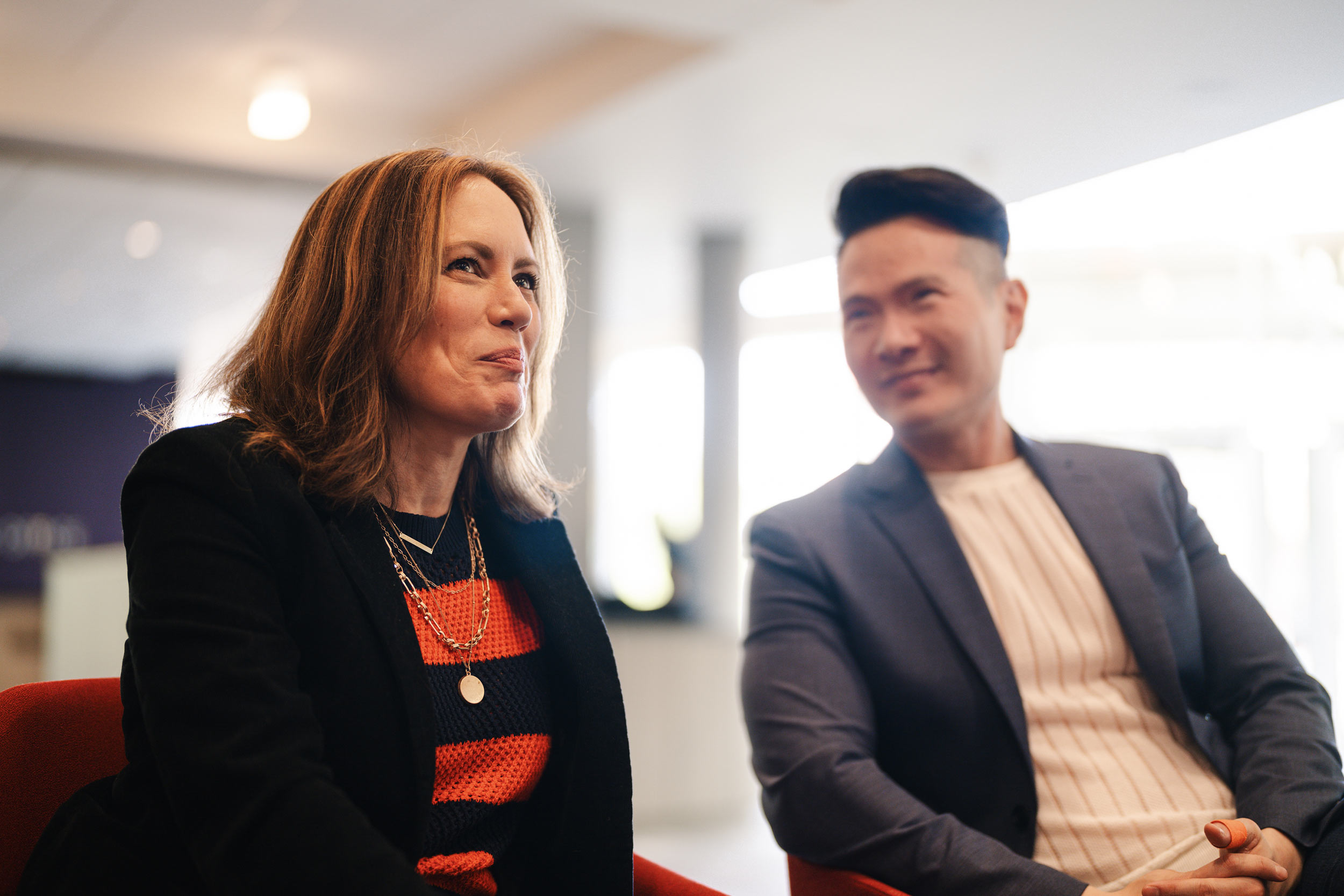 Emily Swallow and James Seol, dressed sharply, chat in the lobby of the Drama Education Building.