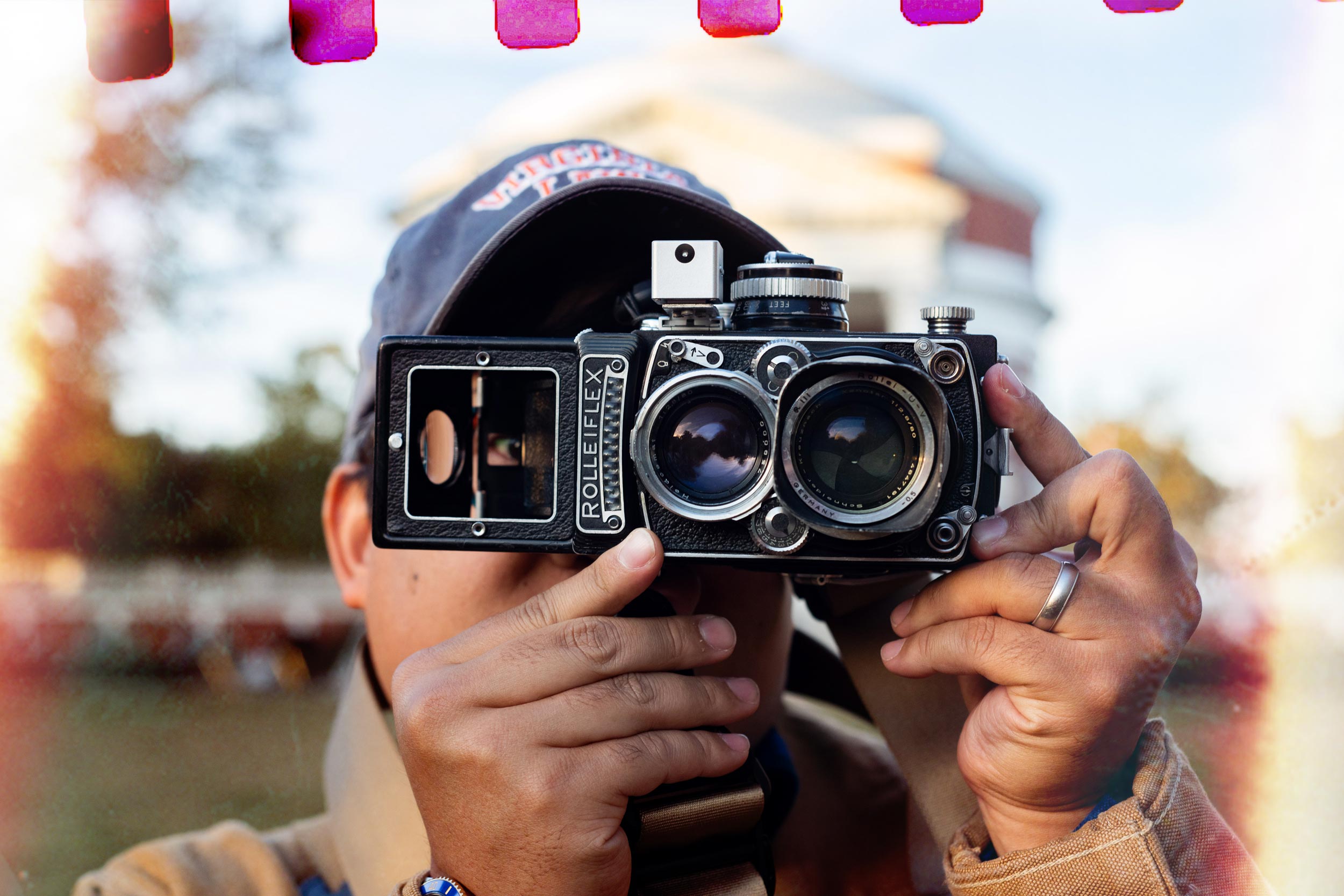 A person stands in front of the rotunda and looks through a classic film camera.