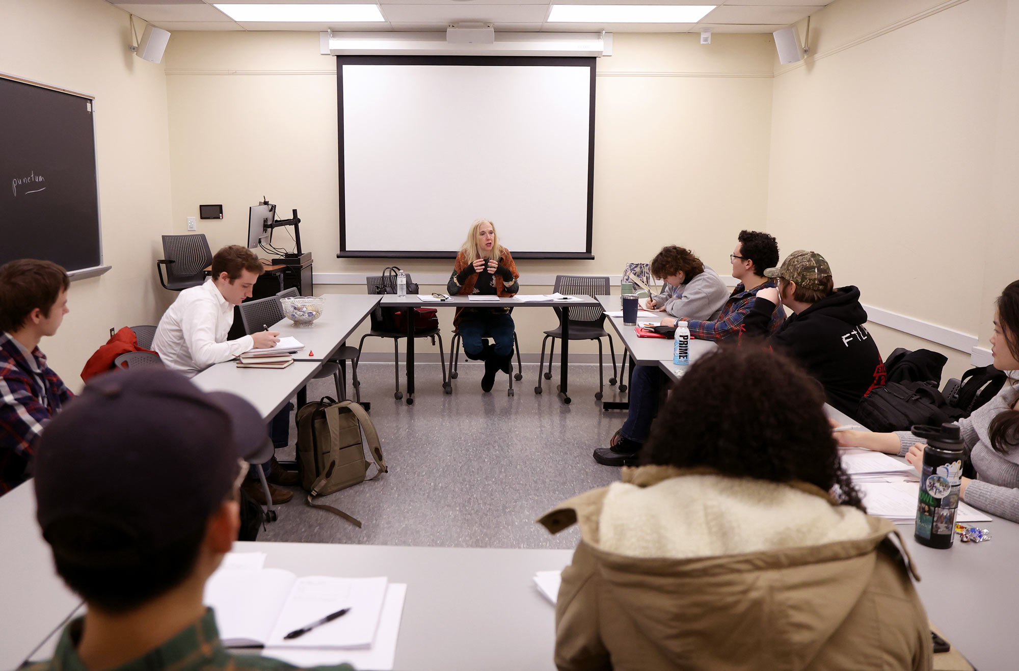 A classroom in which students sit at tables arranged in a circle.