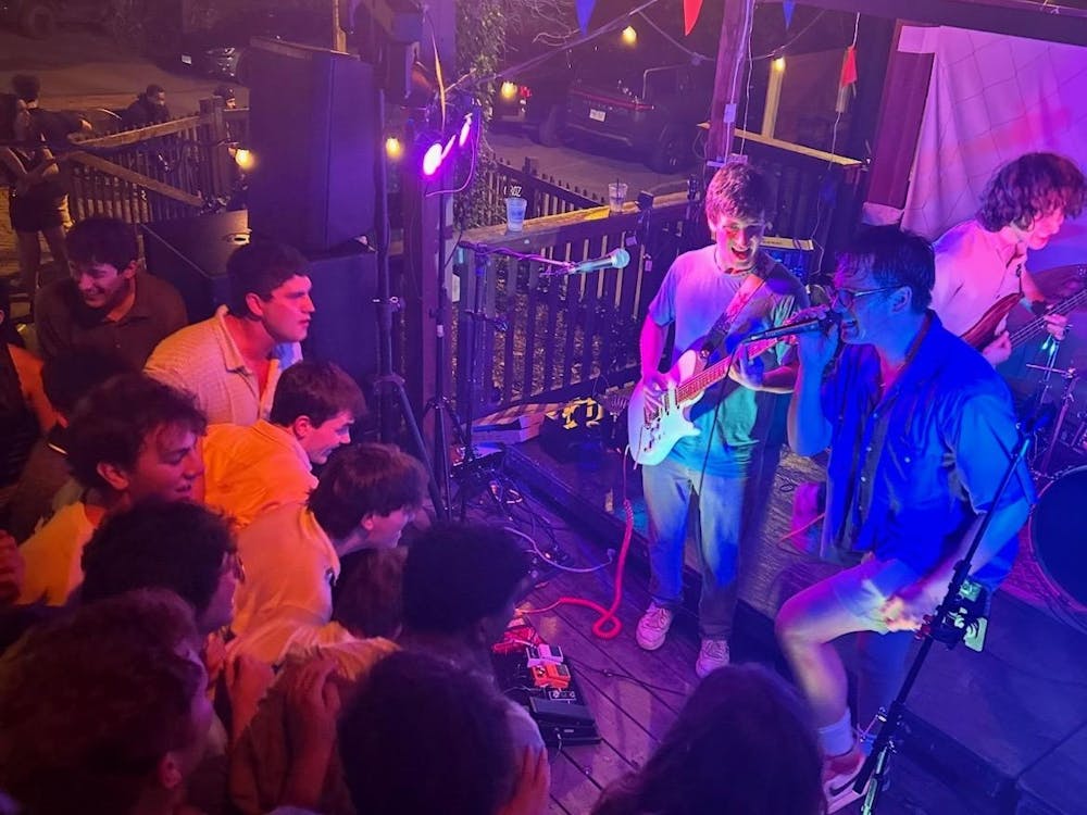 A UVA student band plays at an outdoor venue with colorful lights.
