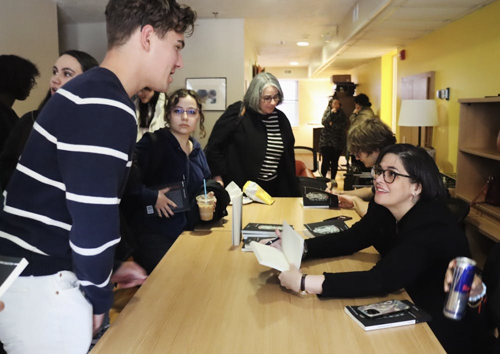 A group of students talk with Elizabeth Mirabal about her poetry publication at a small table.