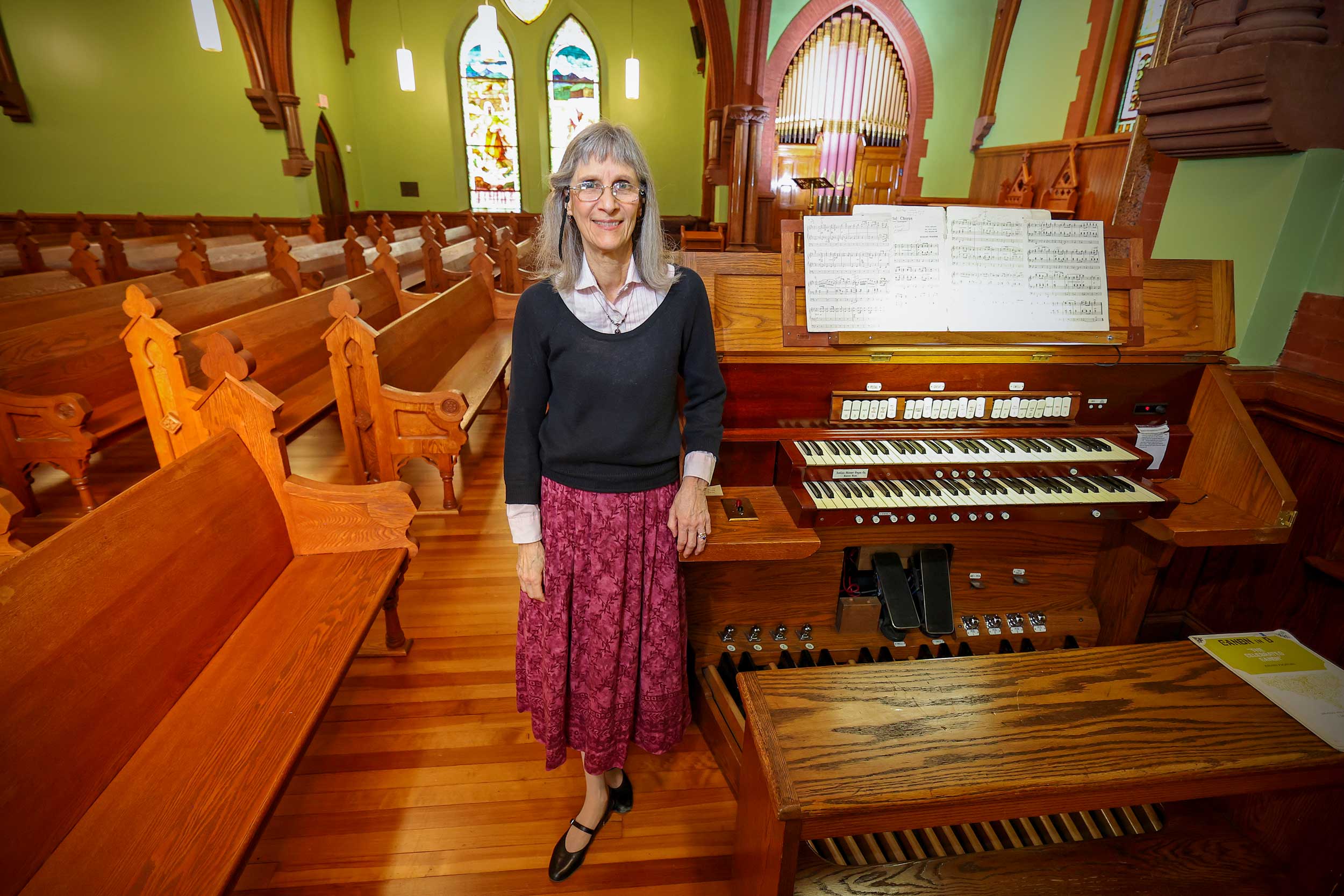 Organist Barbara Moore stands in the UVA chapel in front of the organ that she frequently plays.