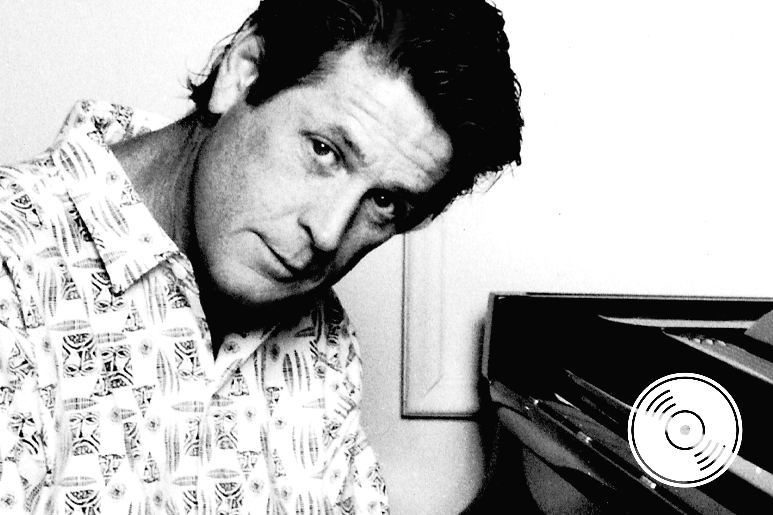 A black and white photo of Brian Wilson sitting at a piano.
