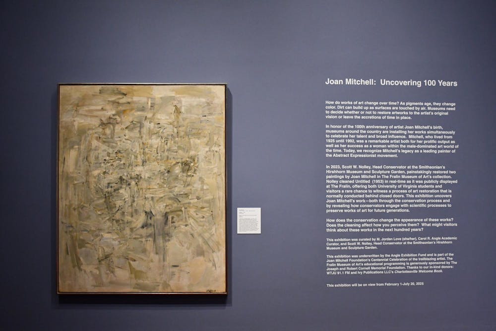 Piece by Joan Mitchell on a blue wall at the exhibition, with the wall text to the right.