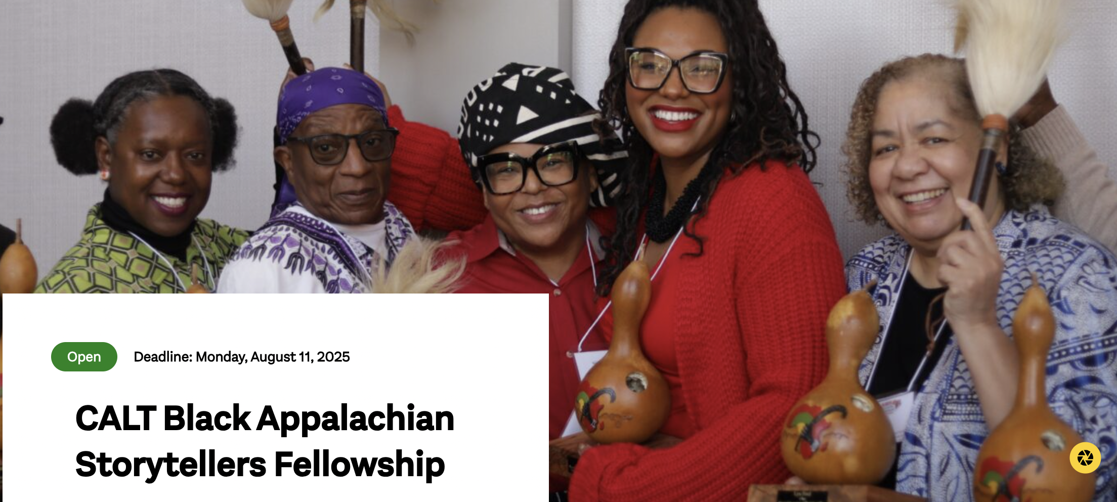 A photo of five African American women stand together, holding various instruments and feather decorations.