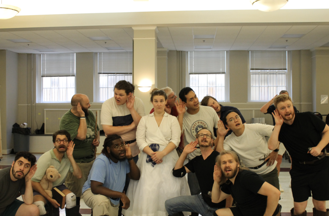 The actors and actresses from the show gather in a clump, all with their hand up to one ear to signal listening.