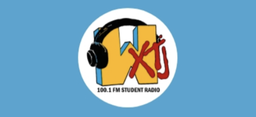The letters WXTJ in a white circle logo, with the W much bigger than the rest and drawn wearing a pair of black headphones.
