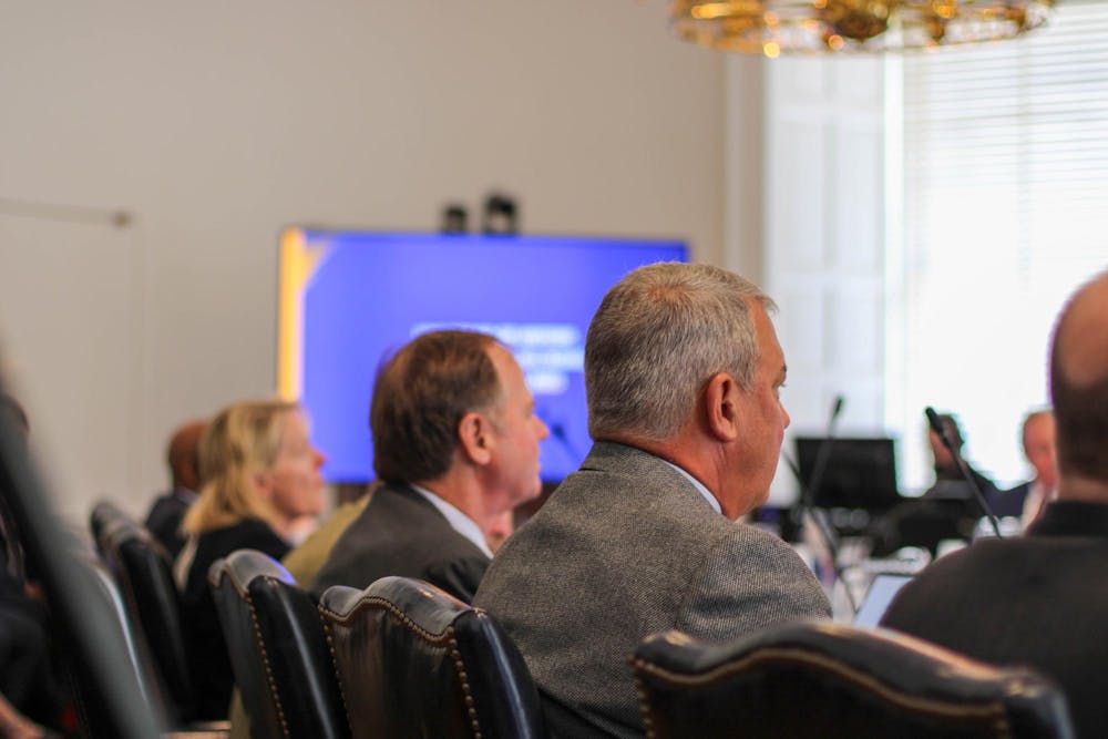 A photo from the back of a lecture where we can see black leather chairs in rows, and the backs of the guests' heads.