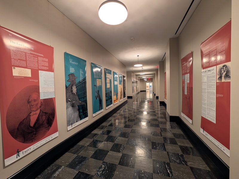 A hallway with checkered floors has informative colors panels on both sides of the hallway walls, blue and red colored. This is a picture of the exhibit.
