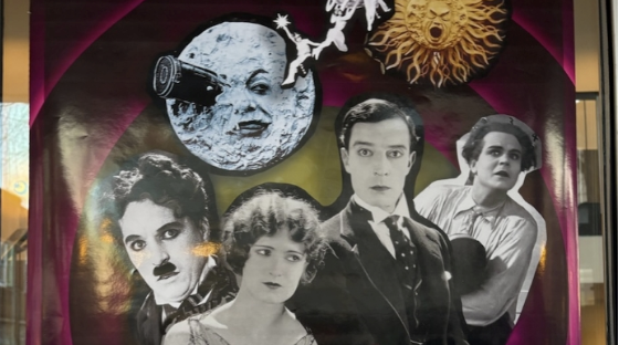 A movie poster with the title, "Silents Scored: Live" in large white letters. Behind the title is a collage of various male and female silent films stars.